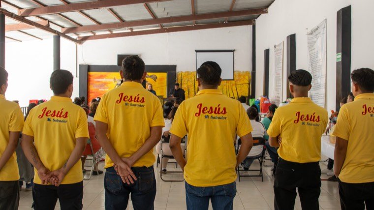 Residentes de pie durante un momento del servicio